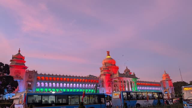 Illuminated Mysore Palace façade at dusk with visitors gathered in the foreground