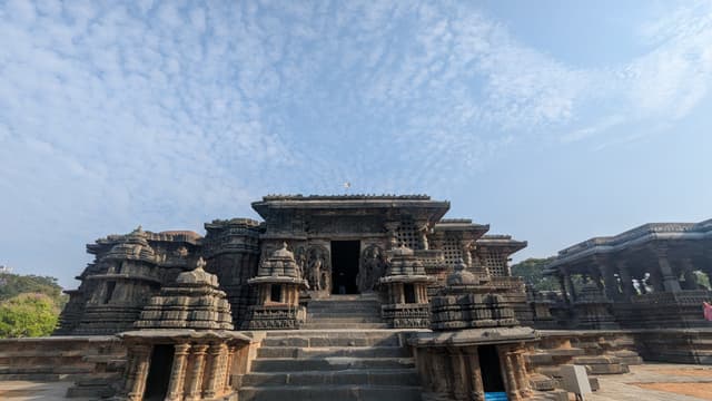 Weathered stone temple with stepped entrance and carved pillars under a clear blue sky