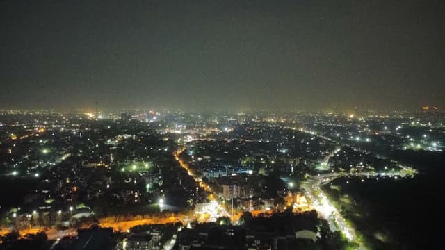 Aerial view of a city at night with dense clusters of lights and illuminated roads stretching into the distance