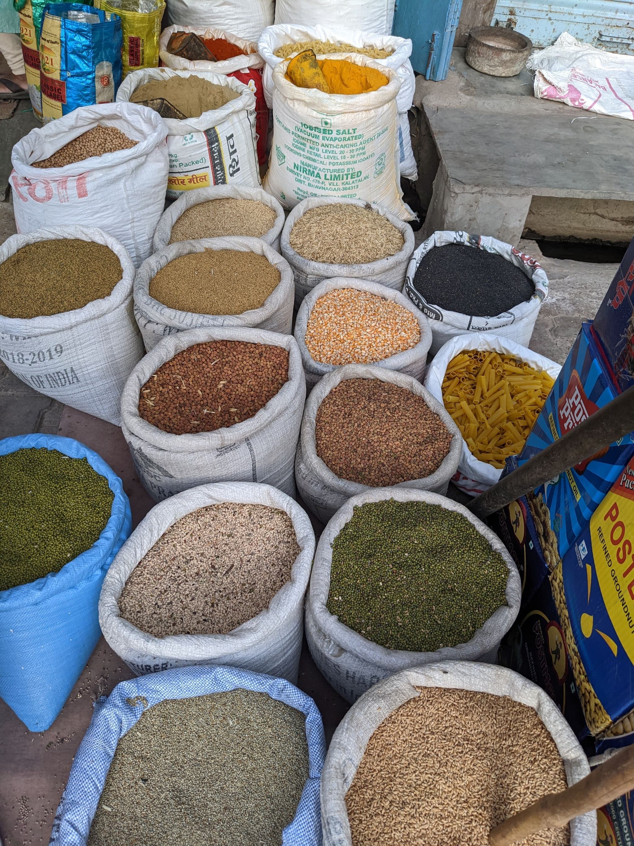 Bags of various grains and spices displayed at a market, featuring different colors and textures